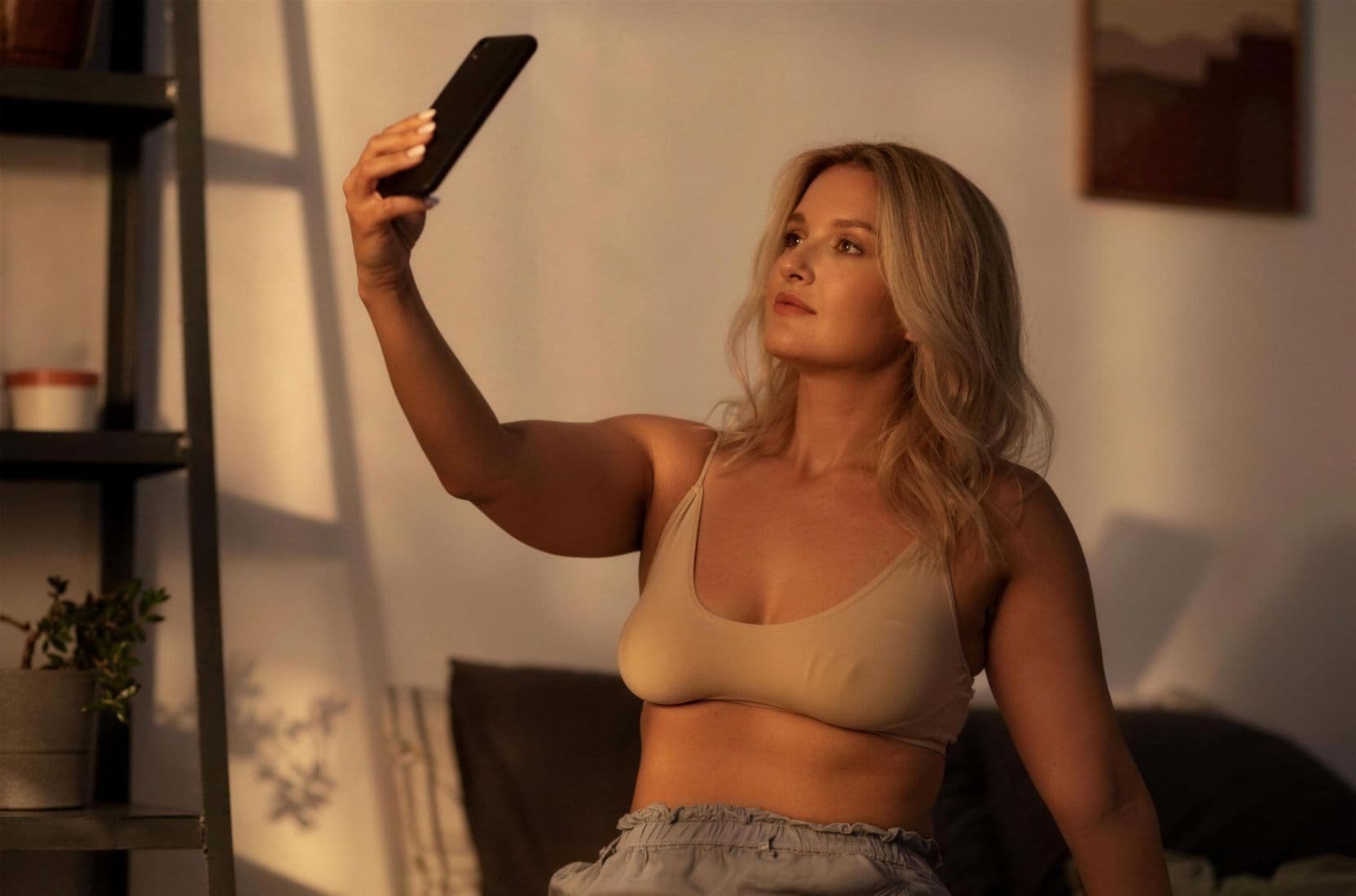 Frau macht Selfie bei Sonnenuntergang drinnen.