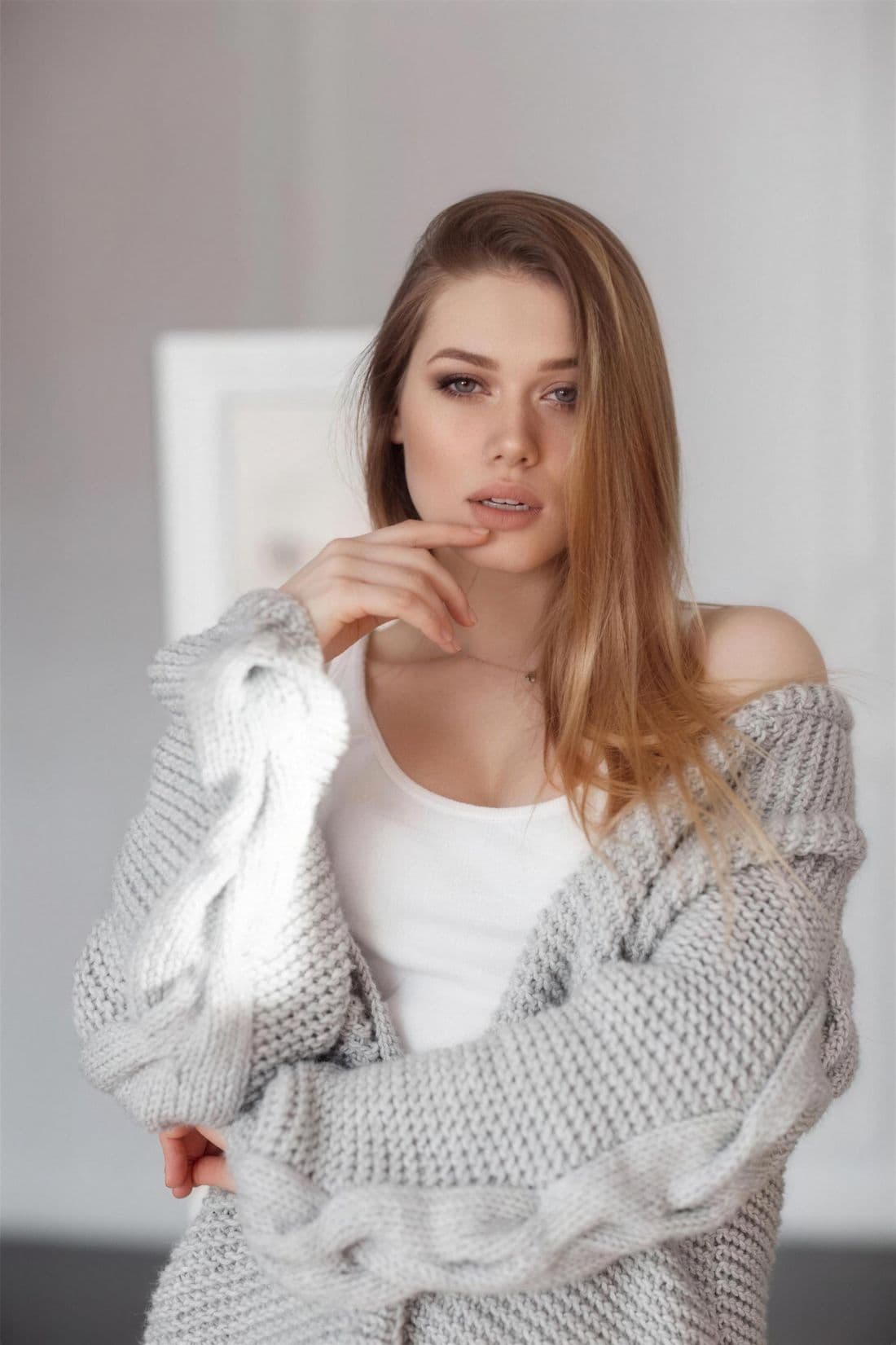 Frau in grauem Pullover schaut nachdenklich.