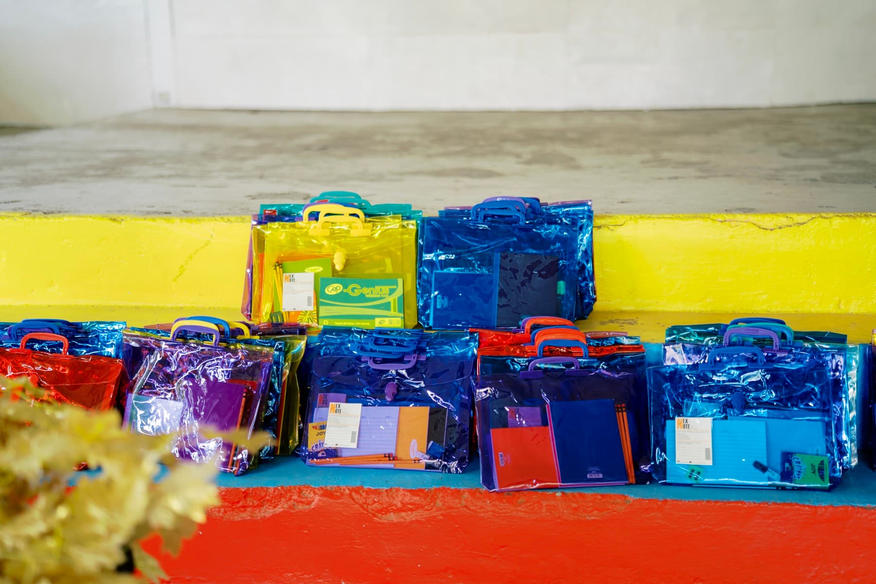 Bunte Taschen mit Heften und Stiften, aufgereiht auf einer Stufe